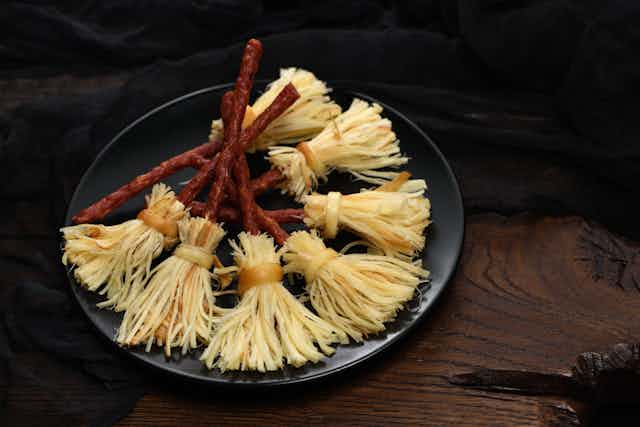 A plate showing cheese and salami snacks made to look like witches' broomsticks