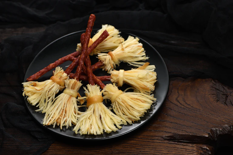 A plate showing cheese and salami snacks made to look like witches' broomsticks