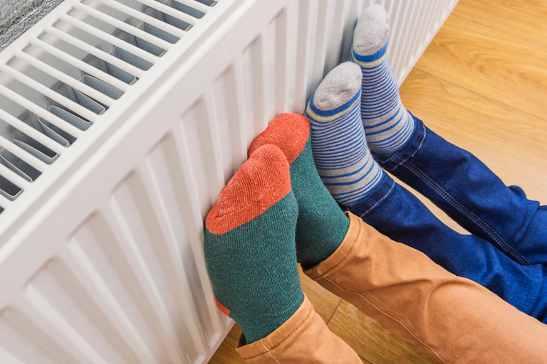 Personnes essayant de se réchauffer les pieds sur un radiateur électrique