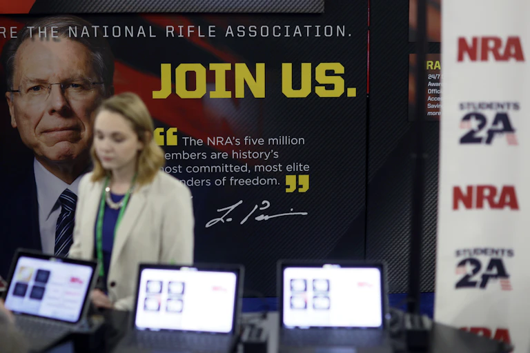 Woman stands next to an NRA poster.