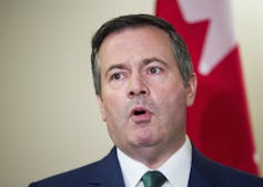 Jason Kenney in front of a Canadian flag.