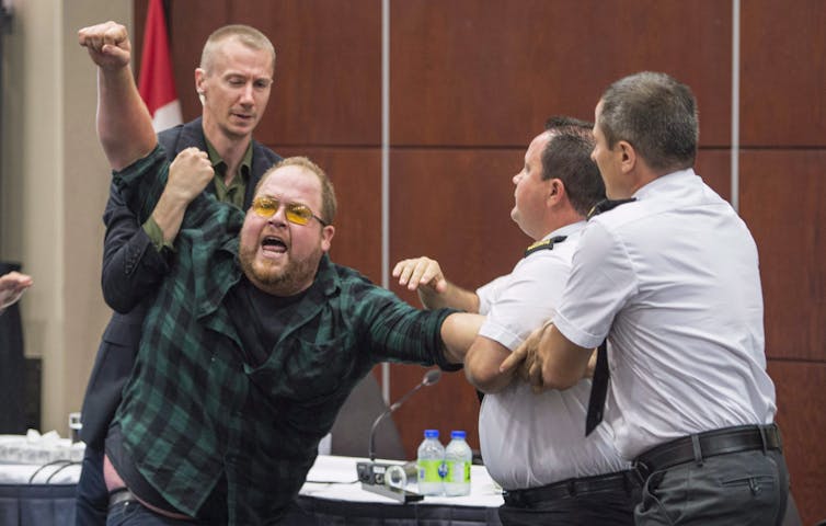 Security guards manhandle a shouting protester.