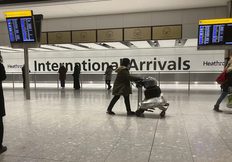 A women pushing a cart through a nearly empty airport.