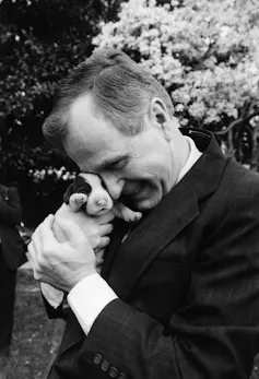 George H.W. Bush cuddles a very young puppy.