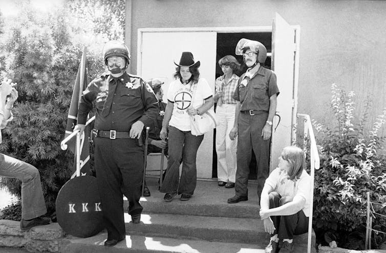 Ku Klux Klan security guards escorting two women members.