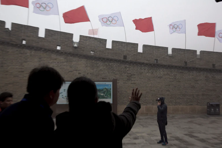 People look up at flags on a section of the Great Wall of China