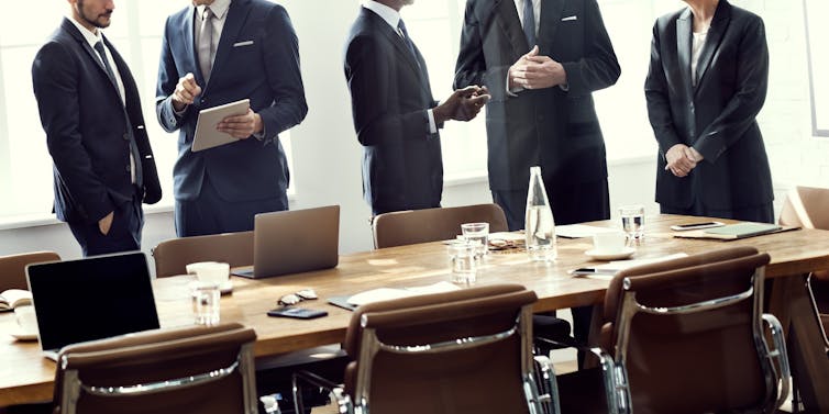 People in suits in modern boardroom.