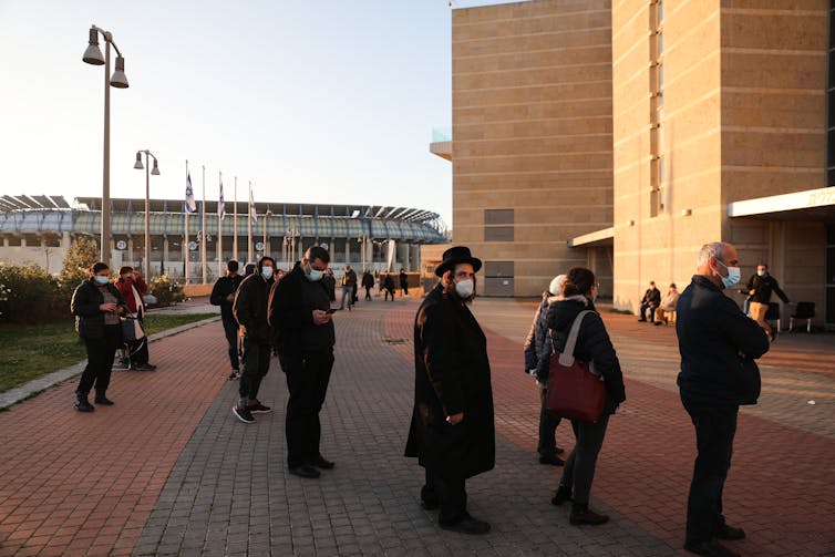 People wait in line to be administered the COVID-19 vaccine in Jerusalem.