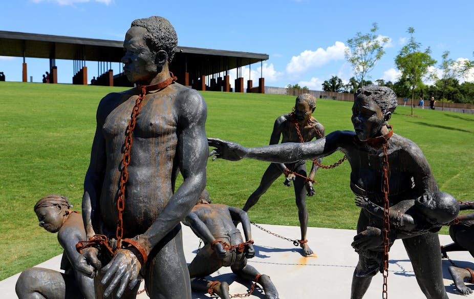 Sculpture showing five naked black men and women in rusted chains on their necks, hands and feet.