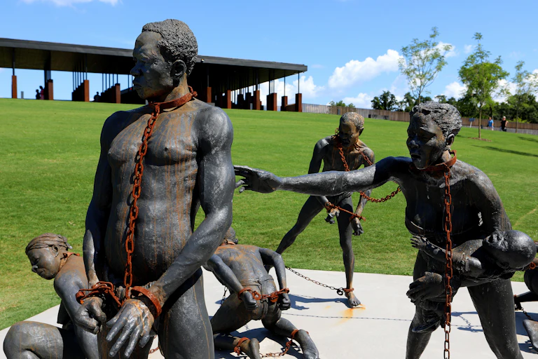 Sculpture showing five naked black men and women in rusted chains on their necks, hands and feet.