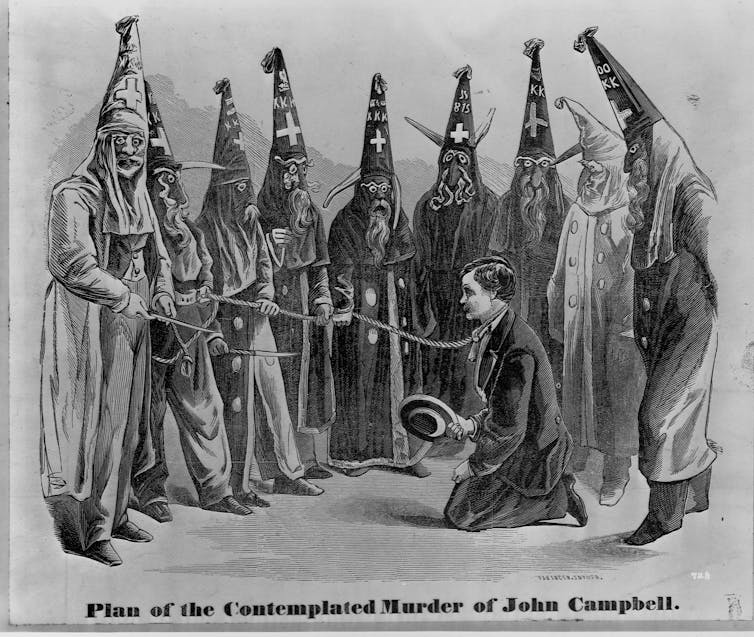 An 1871 engraving depicts a group of Klansmen surrounding a man on his knees with a rope around his neck.