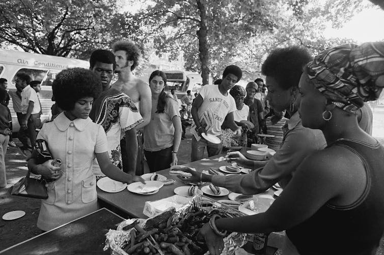 People line up to get food at a table.