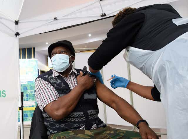 A man wearing a maks gets a coroanvirus vaccine. 