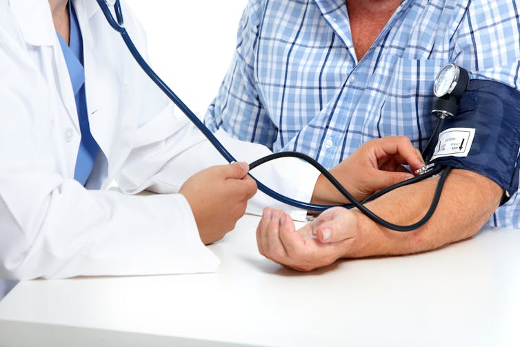 A patients blood pressure being taken by a doctor.