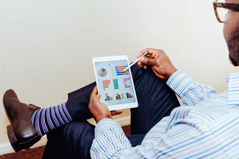 A man looks at financial graphics on his tablet.