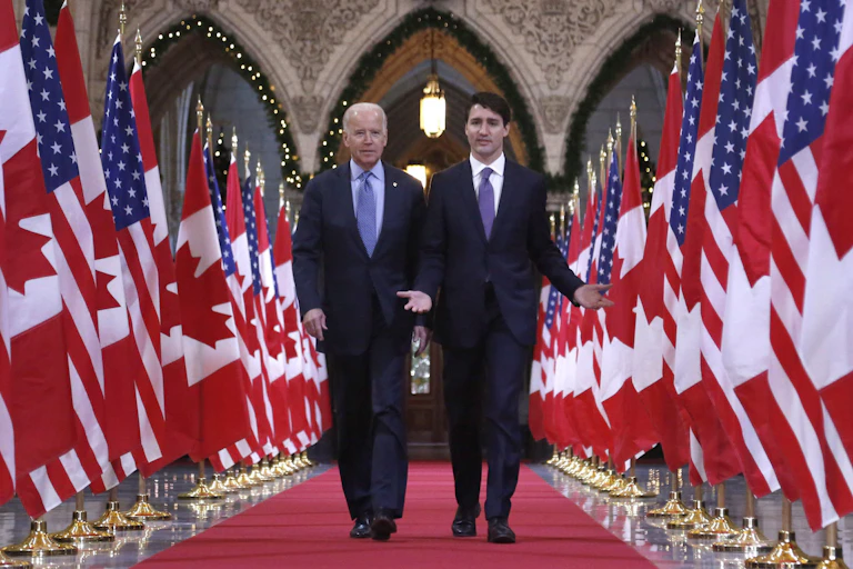 Biden and Trudeau walk down a red carpet flanked with Canadian and U.S. flags.
