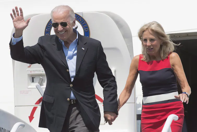 Joe and Jill Biden wave as they exit a plane.