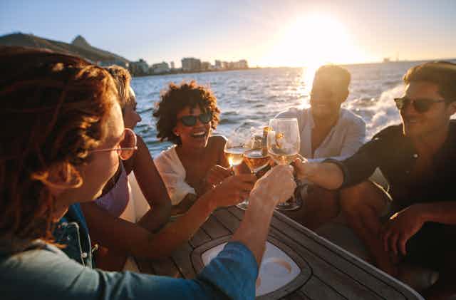 Affluent young people clink glasses on a boat at sunset