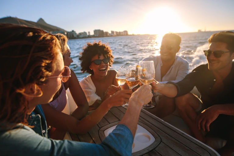 Affluent young people clink glasses on a boat at sunset