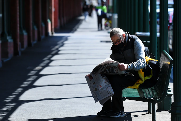 Man on bench reading newspaper
