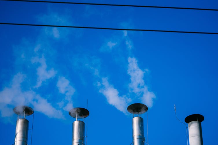 Four smokestacks against a blue sky.