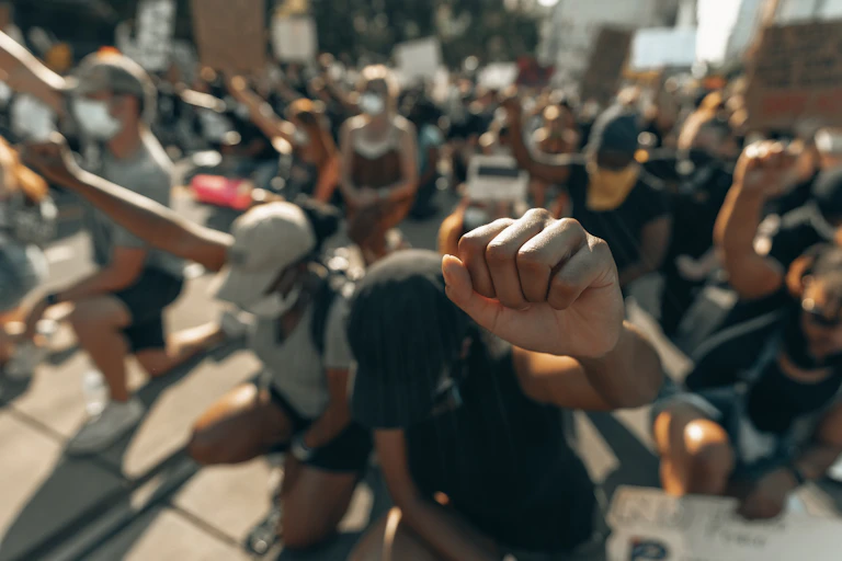 This image shows a close up a fist. All people in the photo are kneeling with raised fists.