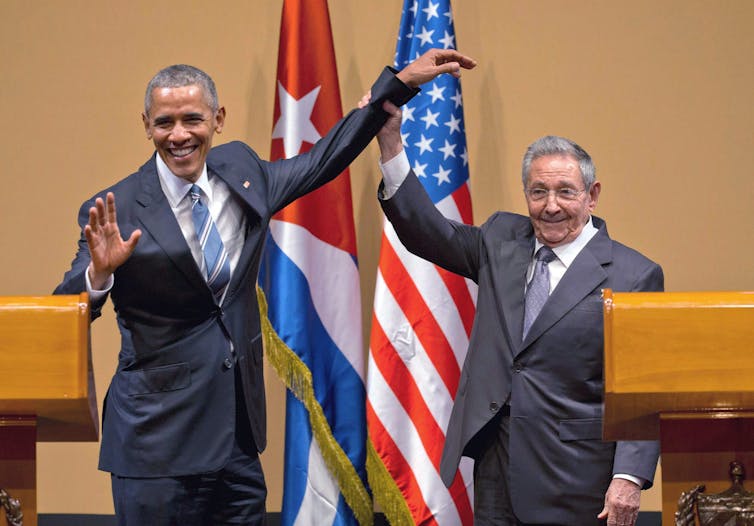 Raul Castro lifts Barack Obama's arm.