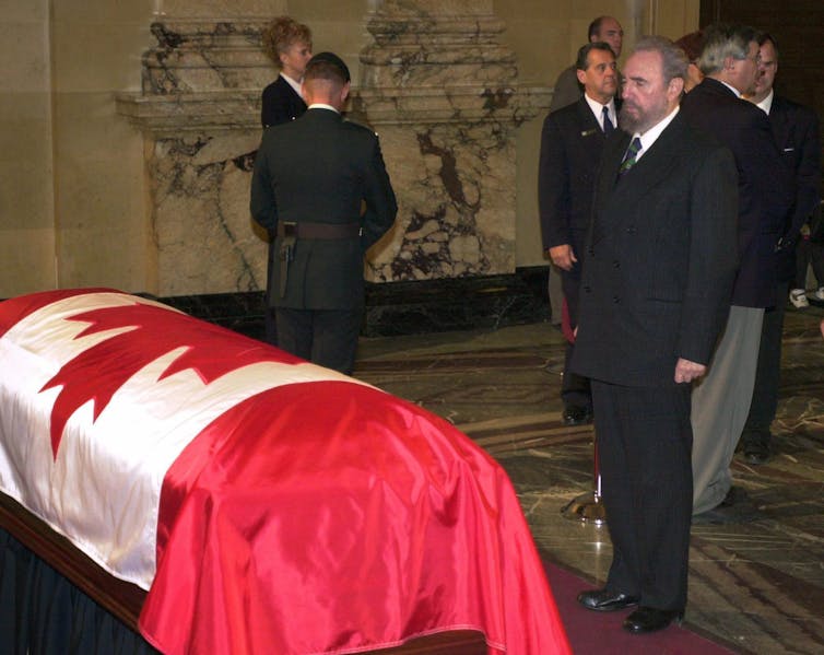 Fidel Castro looks at Pierre Trudeau's casket, draped with a Canadian flag.