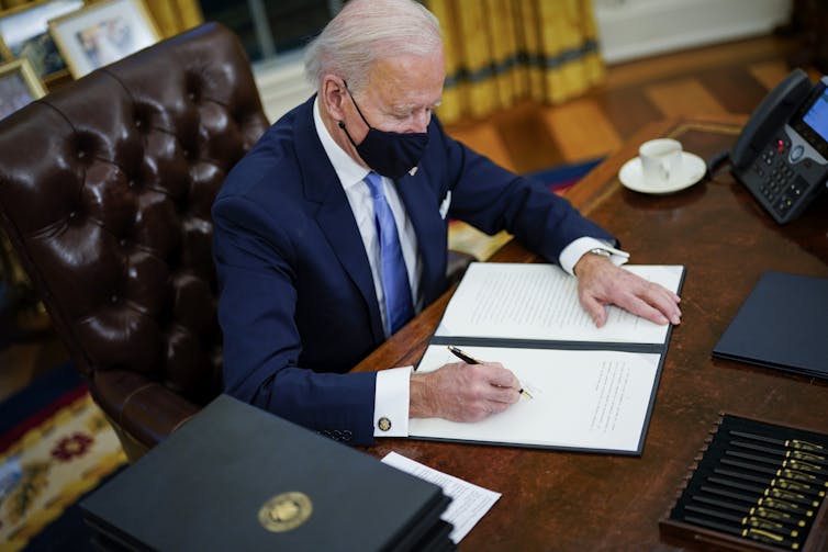 Biden signing an executive order at the Resolute Desk