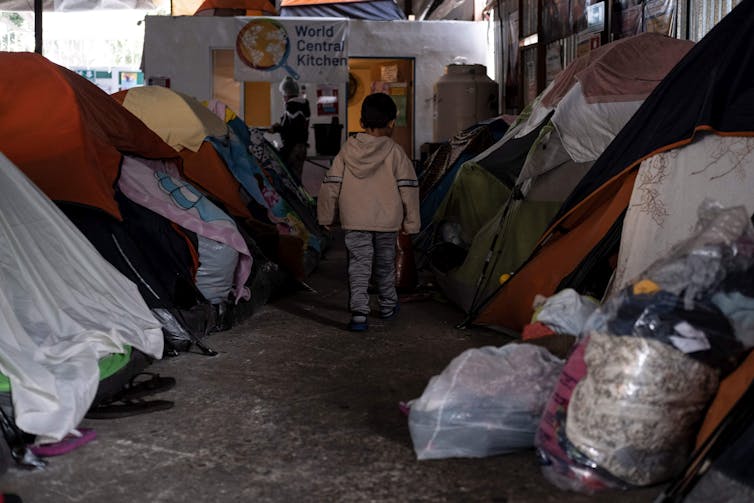 A migrant boy walks amid tents