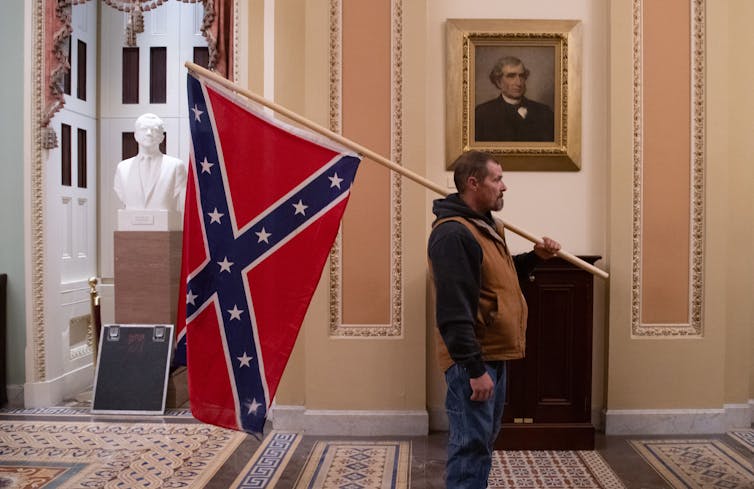 A supporter of President Donald Trump holds a Confederate battle flag outside the Senate chamber.