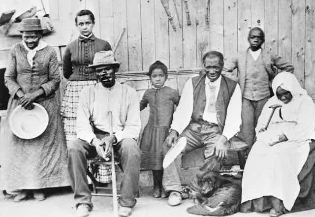 Harriet Tubman poses with a group of Black adults and children who she helped free from slavery.