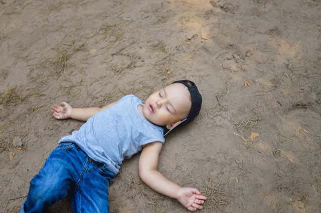 A boy is passed out on the ground.