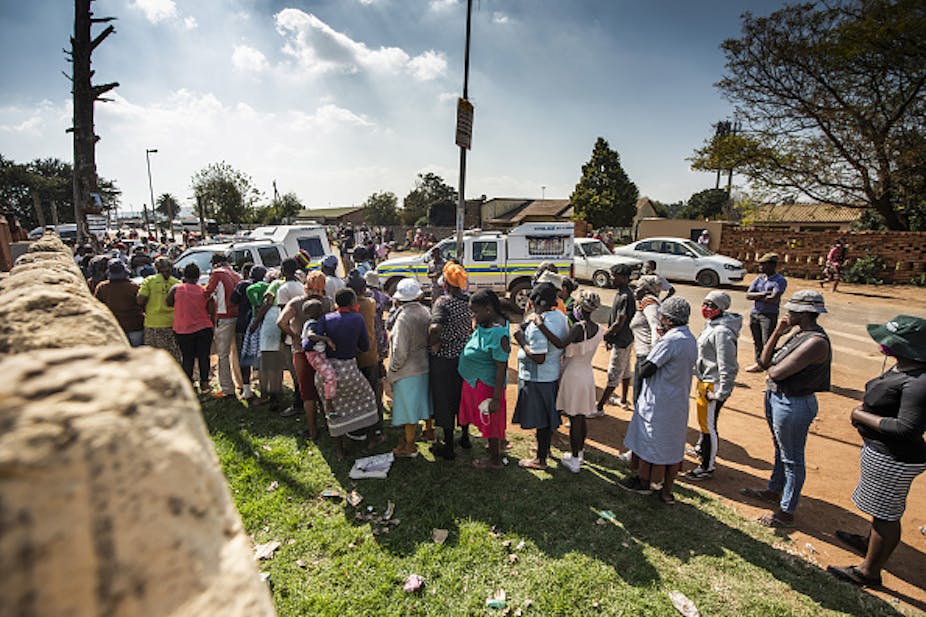 People standing in a line alongside a road