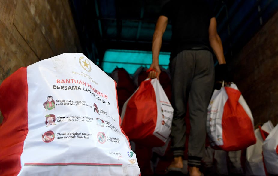 Pekerja menyiapkan paket bantuan sosial di Gudang Food Station Cipinang, Jakarta.