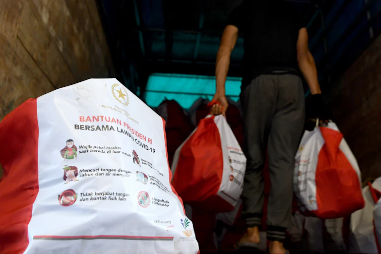 Pekerja menyiapkan paket bantuan sosial di Gudang Food Station Cipinang, Jakarta.