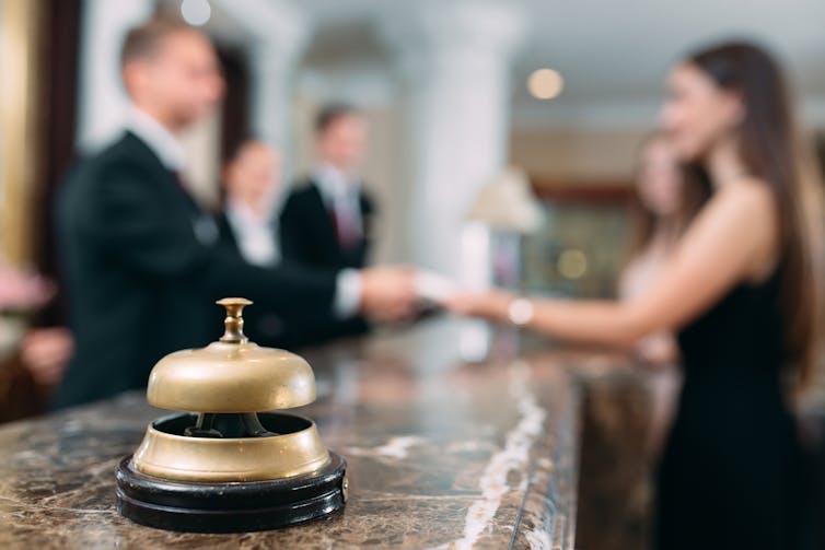 Gold bell at a hotel reception with guests and hotel employees in the background