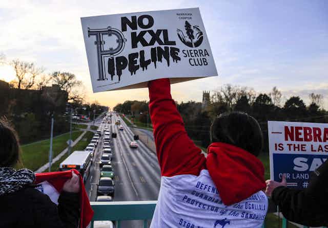 People standing on a bridge with signs.