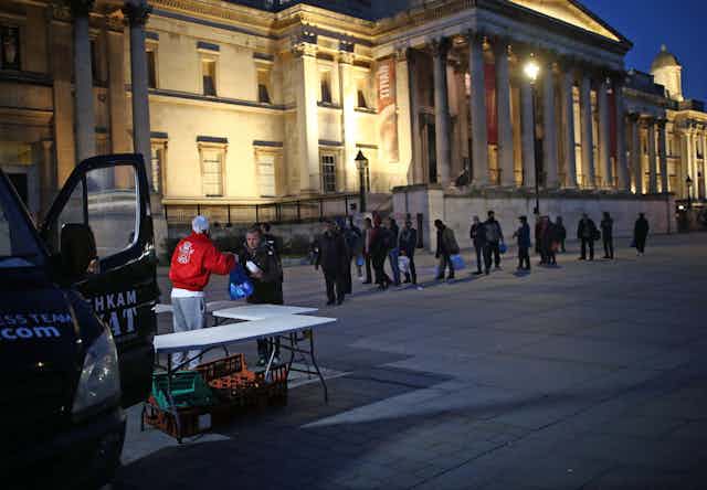 People queue up to receive food from a charity van in London. 
