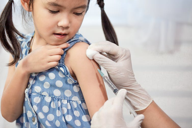 A little girl receives an injection in her arm.