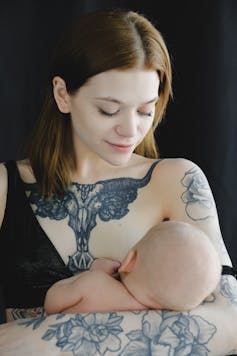 A woman with tattoos breastfeeding her infant