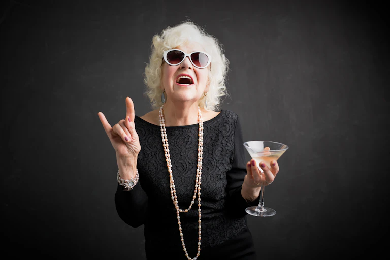 Grandma with glasses and drink in hand showing rock sign