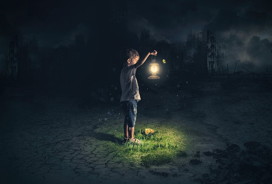 Jeune garçon tenant une lanterne sur fond de paysage d’apocalypse