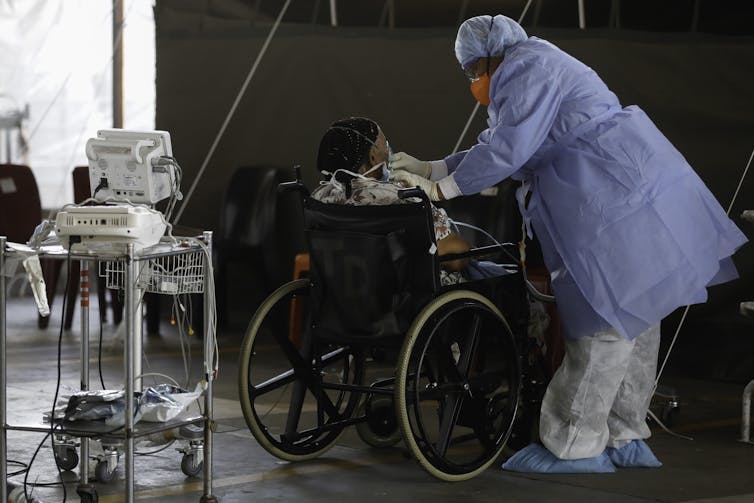 A healthcare worker stands next to a patient at a temporary ward in a South African hospital