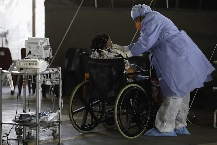 A healthcare worker stands next to a patient at a temporary ward in a South African hospital