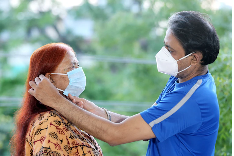 Man putting on face mask for older woman