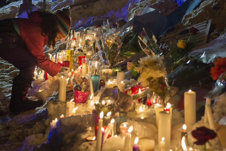 A young girl places a candle at a vigil.