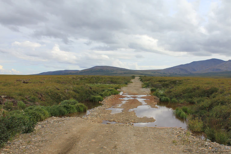 A road with puddles and clouds in the arctic tundra