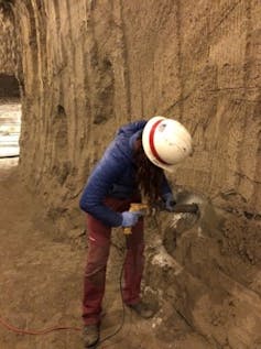 The study author using a drill to take a sample of permafrost in a large tunnel.