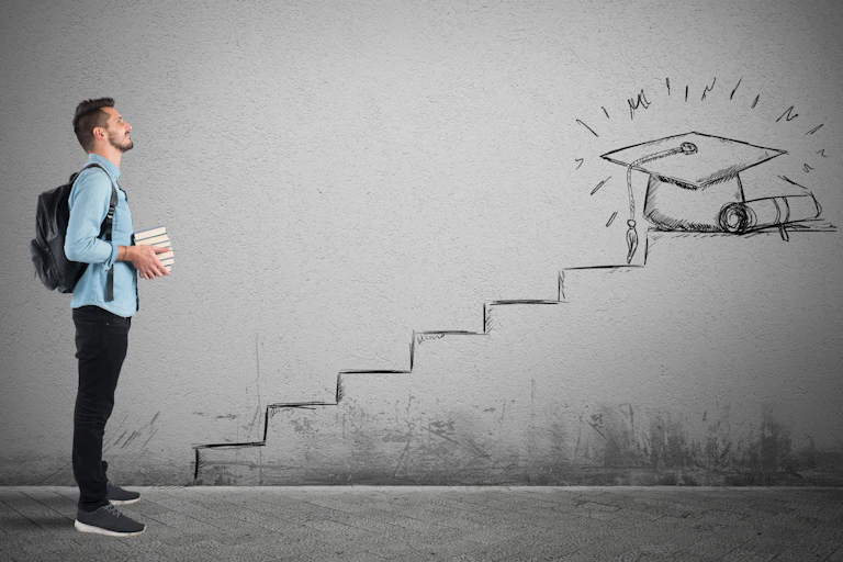 A male student stands in front of steps leading to a degree